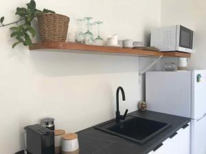 een keuken met een wastafel en een witte koelkast bij Serendipity Adorable Tairua Studio in Tairua