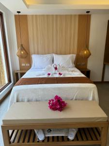 Siargao Island Villas في جنرال لونا: غرفة نوم مع سرير كبير مع الزهور على طاولة