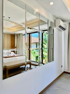 Siargao Island Villas في جنرال لونا: غرفة نوم مع مرآة كبيرة على الحائط