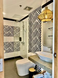 a bathroom with a white toilet and a sink at Siargao Island Villas in General Luna