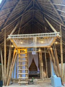 una vista interior de una casa con techo de paja y una escalera en Bamboo House - Ecobreeze, en Sidemen