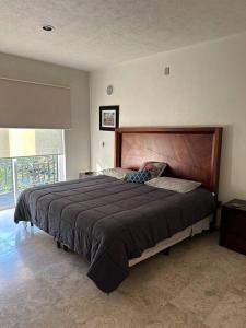 a bedroom with a large bed with a wooden headboard at Residencial Quinta las Acacias, Santa Fe, Juriquilla in Juriquilla