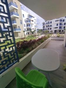 a table and a green chair on a balcony at Welcome everybody in Martil