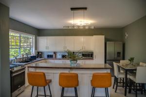 a kitchen with white cabinets and orange bar stools at Serene Mountain View Smart Apt for Restful Stays in Castries