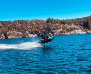 a person on a jet ski in the water at Luxurious cottage outside Bergen with Jacuzzi in Forland