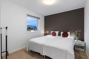 a bedroom with a white bed and a window at Luxurious cottage outside Bergen with Jacuzzi in Forland