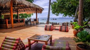 una terraza de madera con sillas, una mesa y el océano en Ten Moons Lipe Resort en Ko Lipe