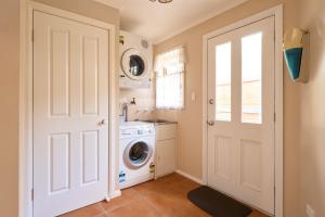 a laundry room with a washing machine and a door at Sunny ways Bicheno in Bicheno