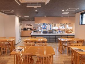 un restaurante con mesas de madera y una cocina en Hotel Taiyo Nouen Furumitsu, en Matsuyama