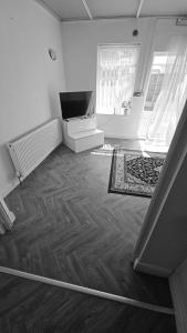 uma sala de estar com televisão e pisos em madeira em Sariyu space em Dagenham