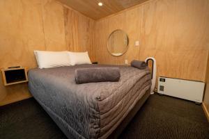 ein Schlafzimmer mit einem Bett und einem Spiegel an der Wand in der Unterkunft Napier Beach TOP 10 Holiday Park & Motels in Napier