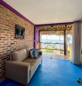 a living room with a couch and a brick wall at Casa Sol Nascente in Itacaré