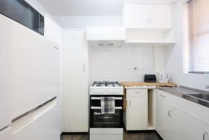 a white kitchen with a stove and white cabinets at Central Perth Loft River Views in Perth