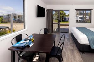 a room with a desk and a bed and a table at Napier Beach Top 10 Holiday Park & Motels in Napier