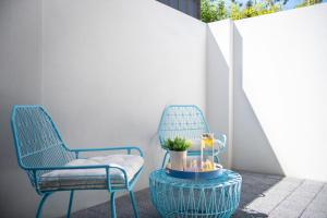 twee blauwe stoelen en een tafel met een glas bij Bright Trendy 2bdrm Apt - Walk to River & Shops in Perth