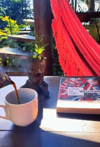 a cup of coffee and a book on a table at Casa Sol Nascente in Itacaré