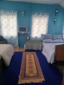 een blauwe kamer met 2 bedden en een tapijt bij Moktan Home Stay 4 in Kalimpong