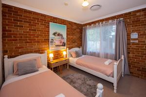 een slaapkamer met 2 bedden en een bakstenen muur bij A Fairy Wren Cottage in Broadwater