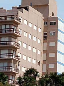 un edificio alto con palmeras delante en EDIFICIO NOVOMAR 5to Piso en Mar de Ajó