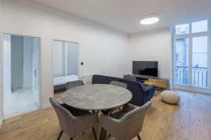 a living room with a table and chairs and a couch at T3 Hypercentre - Neuf, Equipé avec Parking à Proximité in Grenoble