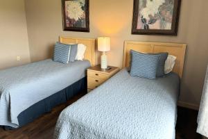 1 dormitorio con 2 camas y mesita de noche con lámpara en Mountain View Condos #3407, en Pigeon Forge