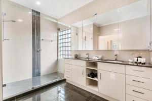 un bagno bianco con doccia e lavandino di Amazing Canal House with Private Jetty, Gym & Pool a Mooloolaba