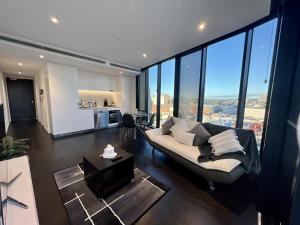 - un salon avec un canapé et de grandes fenêtres dans l'établissement Luxury 1-Bed with Infinity Pool, Gym & Parking, à Brisbane