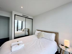 - une chambre avec un grand lit blanc et un miroir dans l'établissement Luxury 1-Bed with Infinity Pool, Gym & Parking, à Brisbane