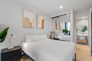 een witte slaapkamer met een groot bed en een spiegel bij MadeComfy Inner City Designer 2-Bed Apartment in Melbourne