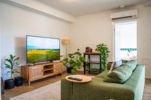a living room with a green couch and a flat screen tv at Tranquil 2-Bed Inner City Retreat with Parking in Brisbane