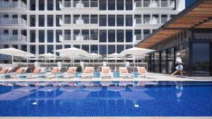 a swimming pool with chairs and umbrellas next to a building at 2-Bed with Pool, Gym, Parking and Balcony in Brisbane