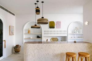 una cucina con pareti bianche e bancone con sgabelli di Basq House a Byron Bay