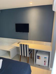 a room with a desk with a tv on a wall at hihome - Royale in Cabo Frio