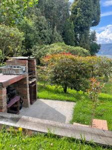 a stone fireplace in a garden with trees and flowers at Mirador Valeisa in Guatavita