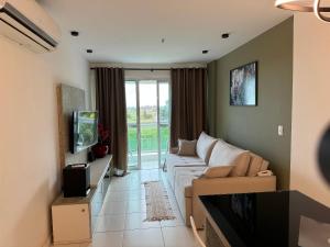 a living room with a couch and a tv at hihome - Mandai Flat in Cabo Frio