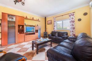sala de estar con sofá de cuero y TV en Villa Raquel, en Pollensa
