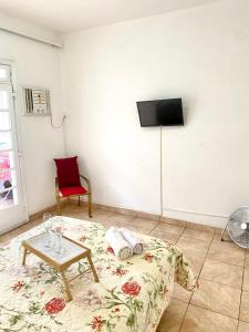 sala de estar con mesa y TV en la pared en Apartamento Teresópolis - Centro en Teresópolis