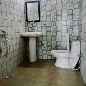 a bathroom with a sink and a toilet and a mirror at Jaishnavi Homestay And Restaurant in Mukteswar +87 photos