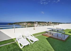 a patio with white chairs and a picnic table on a roof at Stunning Ocean Views With Manly At Your Doorstep in Sydney