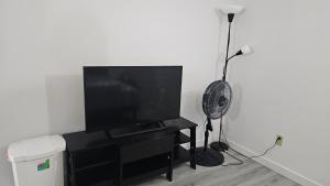 a black entertainment center with a flat screen tv and a fan at Bright and Cozy Room with Free Parking in Edmonton