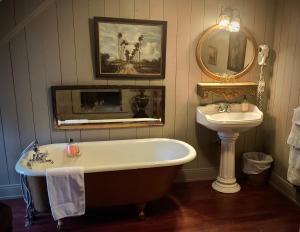 ein Badezimmer mit einer Badewanne, einem Waschbecken und einem Spiegel in der Unterkunft Le Mange Grenouille in Bic