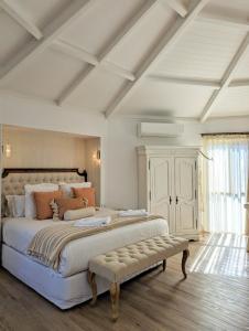 um grande quarto branco com uma cama grande e um banco em Austinvilla Estate em Mudgeeraba