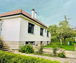 una casa blanca con flores en el patio en Stylish, Calm and Green Home Stay, en Saint-Fargeau-Ponthierry