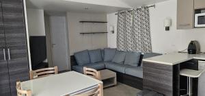 a living room with a blue couch and a kitchen at Mobil home La palmyre 8 Pers in Les Mathes