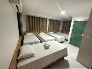 Habitación con 4 camas y pared de cristal. en Hotel Trevo Caruaru en Caruaru
