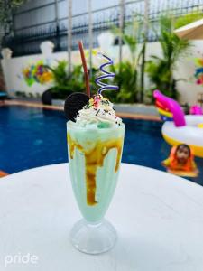 een dessert in een glas op een tafel naast een zwembad bij Pride Resort Cambodia in Phnom Penh