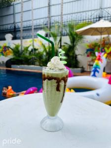 een milkshake op een tafel naast een zwembad bij Pride Resort Cambodia in Phnom Penh