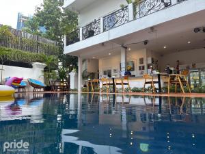een huis met een zwembad met een tafel en stoelen bij Pride Resort Cambodia in Phnom Penh