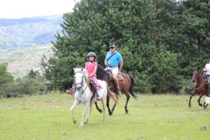 a group of people riding horses in a field at Hotel Ráquira Silvestre Lodge in Tinjacá