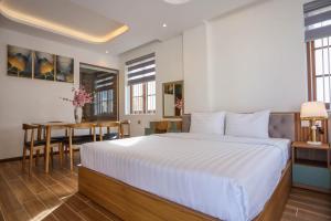 a bedroom with a large bed and a table at Mimosa Hotel Phú Quốc in Phu Quoc